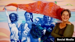 La pintora cubana Ana Albertina Delgado junto a su obra "El techo del mundo" 2023. (Facebook/entrevistada)