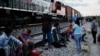 Migrantes observan un tren en marcha junto a las vías en las que esperan para subir a bordo de un vagón, con el fin de dirigirse a la frontera de México con EEUU.