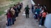 Un grupo de migrantes espera a ser procesado junto al muro fronterizo, en Eagle Pass, Texas. (AP/Dario Lopez-Mills, File)