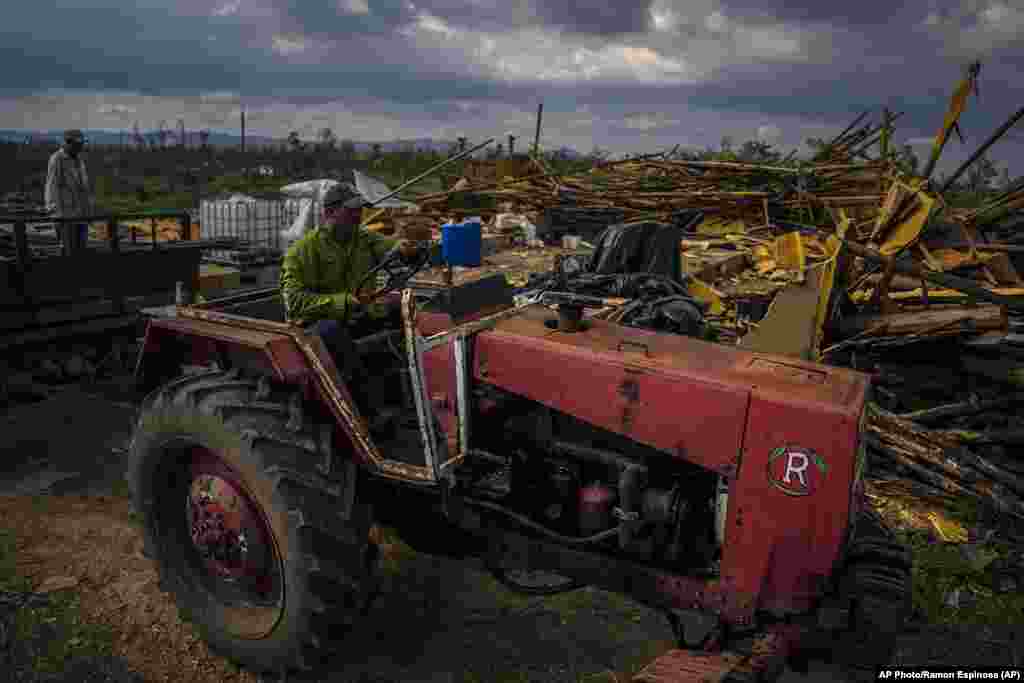 El productor de tabaco Hirochi Robaina conduce su tractor frente a graneros de tabaco destruidos en su finca una semana después del huracán Ian en San Luis, en la provincia de Pinar del Río. 