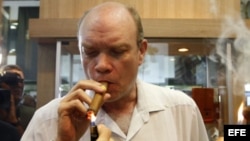 El ministro cubano de Inversión Extranjera, Rodrigo Malmierca (c), enciende un puro durante la inauguración de la feria comercial del XIV Festival del Habano, en La Habana.