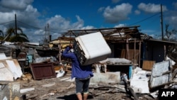 Un residente lleva a cuestas una lavadora dañada después del paso del huracán Ian en La Coloma, provincia de Pinar del Río, Cuba.