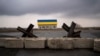 Barreras antitanque yacen frente a una casa pintada con los colores de la bandera ucraniana en las afueras de Kiev, Ucrania. (AP Foto/Rodrigo Abd)