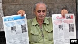 Un vendedor de periódicos en La Habana muestra el diario oficial Granma y Juventud Rebelde, con la misma portada.