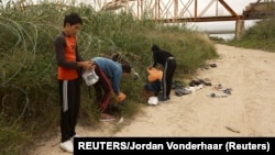 Un grupo de migrantes de Cuba revisa sus teléfonos poco después de cruzar el Río Grande en Eagle Pass, Texas, el 18 de diciembre de 2022.