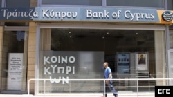 Un hombre pasa delante de una oficina del Banco de Chipre en Nicosia, Chipre.