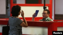 Un oficial de inmigración chequea el pasaporte de una mujer en el Aeropuerto Internacional José Martí de La Habana.