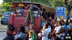 Varias personas suben a un camión de transporte de pasajeros en Santiago de Cuba.