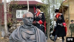 Cosacos rusos con su uniforme posan junto a busto de Putin.