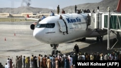 Personas de pie sobre un avión en el aeropuerto de Kabul el 16 de agosto de 2021. Miles de personas están buscando salir del país ante la llegada de los talibanes al poder.
