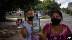 Una imagen que la prensa oficial no divulga: Servilia Pedroso (der.), madre del estudiante de 18 años Eloy Bárbaro Cardoso, y Yaquelin Cruz, madre de Dariel Cruz, dos manifestantes del 11J en La Güinera, muestran sus fotos. (AP/Ramón Espinosa).