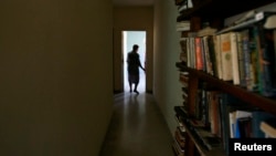 Una mujer camina cerca de un librero en su apartamento en La Habana. REUTERS/Claudia Daut