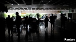 Personas se aglomeran en la oscuridad en un centro comercial en medio de un apagón en Venezuela.