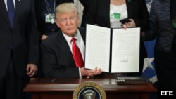 El presidente estadounidense, Donald J. Trump (c), enseña la firma de la orden ejecutiva para destinar fondos federales a la construcción del muro con México durante una ceremonia en el Departamento de Seguridad Nacional en Washington, Estados Unidos, ho