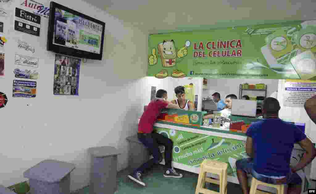 Varios jóvenes atienden a los clientes en un negocio de reparación de móviles, en La Habana.
