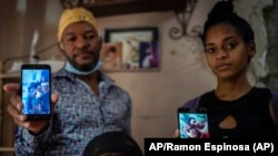 Odlanier Santiago Rodríguez, su tío Emilio Román y la nuera de éste, María Carla Milán Ramos, muestran fotos de los tres hijos de Román que aún permanecen detenidos por participar en las protestas del 11 de julio.