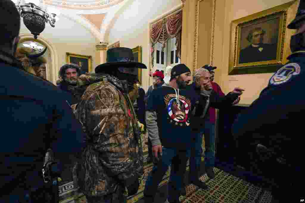 Manifestantes caminan mientras los oficiales de policía del Capitolio de los Estados Unidos observan en un pasillo cerca de la cámara del Senado, en el Capitolio, en Washington. (AP / Manuel Balce Ceneta)