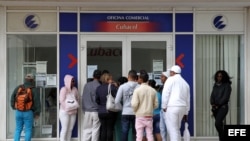 Varias personas hacen fila frente a una oficina de la empresa estatal cubana Etecsa