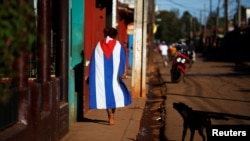 Una persona camina vistiendo una bandera cubana el Alquizar. REUTERS/Tomas Bravo