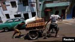 Residentes transportan bloques en una carretilla por una calle de la La Habana.