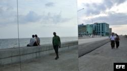 Dos hombres caminan junto a la obra ""Happily Ever After", de la artista cubana Rachel Valdés Camejo, colocada en el malecón de La Habana (Cuba) como parte de la XI Bienal de La Habana.