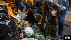 Varias personas buscan comida entre bolsas de basura en Caracas.