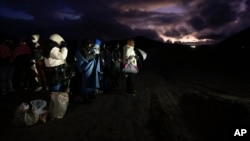 Migrantes solicitantes de asilo se envuelven en mantas para protegerse del viento y la lluvia mientras esperan a ser procesados tras cruzar la frontera con México, en Jacumba Hot Springs, California.