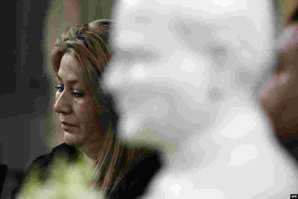 Floribeth Mora (i) escucha las preguntas de los periodistas a una estatua de Juan Pablo II (d).