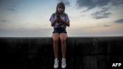 Una joven intenta conectarse a Internet en el Malecón habanero.