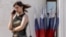 Una mujer habla por teléfono mientras pasa junto a banderas nacionales rusas en Kursk. (REUTERS/Maxim Shemetov)