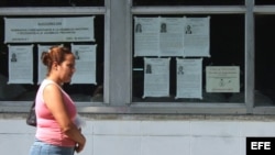 Una mujer camina junto a carteles alusivos a las elecciones de los delegados a las asambleas nacionales y provinciales del Poder Popular en Cuba.