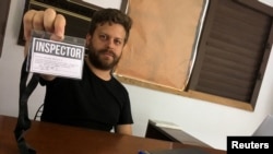El artista cubano Leandro Feal sostiene una tarjeta de presentación que dice: "inspector", un performance que denuncia la figura de control artístico amparada bajo el Decreto Ley 349.