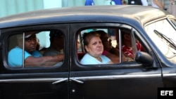 Varias personas van en un taxi de fabricación estadounidense en una calle de La Habana (Cuba).
