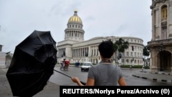 Un turista chino ajusta su paraguas en medio de una tormenta frente al capitolio de La Habana. (REUTERS/Norlys Perez/Archivo)