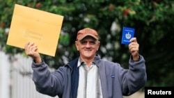 El cubano Pedro Ravelo muestra su pasaporte luego de recibir la visa de EEUU en la Embajada de EEUU en Bogotá el 22 de febrero de 2018. REUTERS/Jaime Saldarriaga