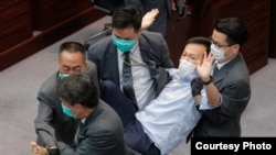 Guardias de seguridad arrastran al legislador pro democracia Ray Chan durante una reunión legislativa el 8 de mayo de 2020 en Hong Kong.