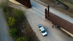 Un oficial de Aduanas y Protección Fronteriza de Estados Unidos habla con los migrantes después de que fueron detenidos y puestos bajo custodia, el domingo 21 de marzo de 2021, en Abram-Perezville, Texas.