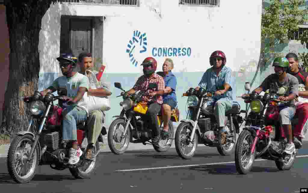 Varias personas viajan en moto-taxi particulares por las calles de Santiago de Cuba.